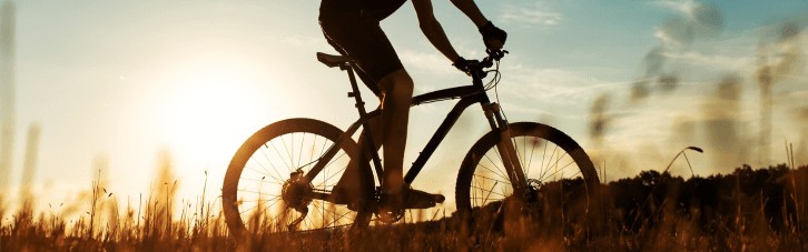 Mann fährt auf einem Fahrrad bei Sonnenuntergang