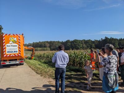 Teilnehmer des Kommunalzirkels begutachten eine Mähmaschine, die den Rasenstreifen neben einem Feld bearbeitet (Arbeitstreffen in Rohr am 28. September 2023)