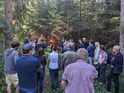 Teilnehmer des Kommunalzirkels stehen in einem Wald (Arbeitstreffen in Rohr am 28. September 2023)