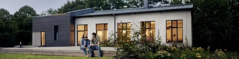 Zwei Menschen sitzen vor einem Haus auf der Terrassenstufe