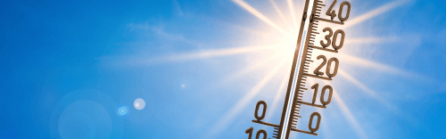 Ein Thermometer wird in die Luft vor der Sonne mit blauen Himmel gehalten