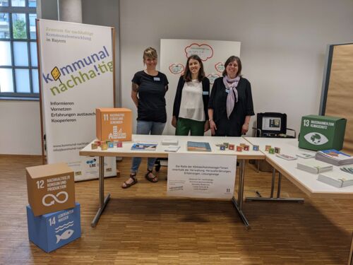 Das Team des Zentrums für nachhaltige Kommunalentwicklung steht an einem Messestand bei dem Netzwerktreffen für Klimaschutzmanager*innen in Regensburg 2022